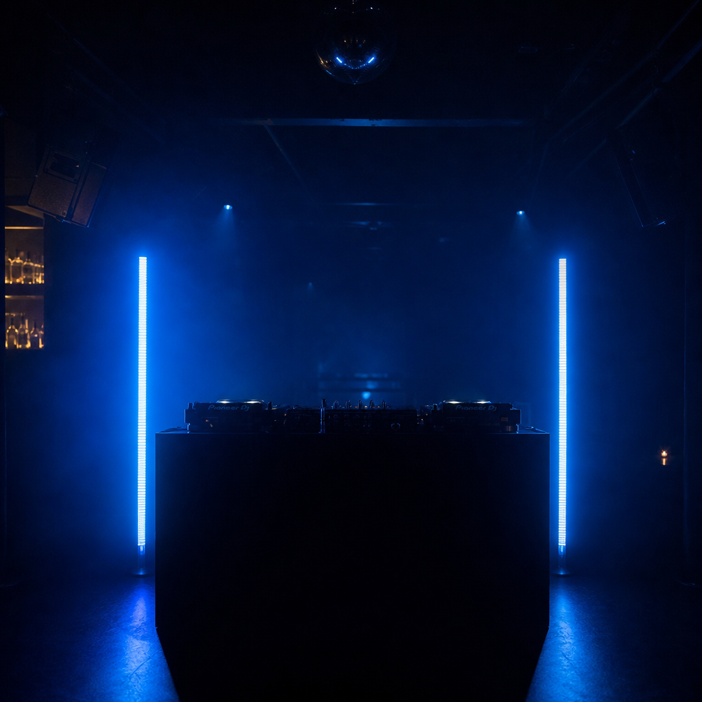 DJ booth in dark venue flanked by two wireless LED pixel tubes